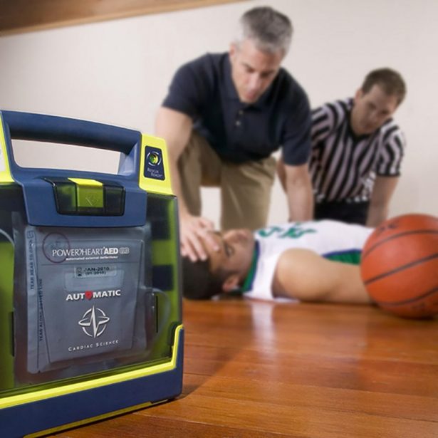Two men leaning over an unconscious basketball player