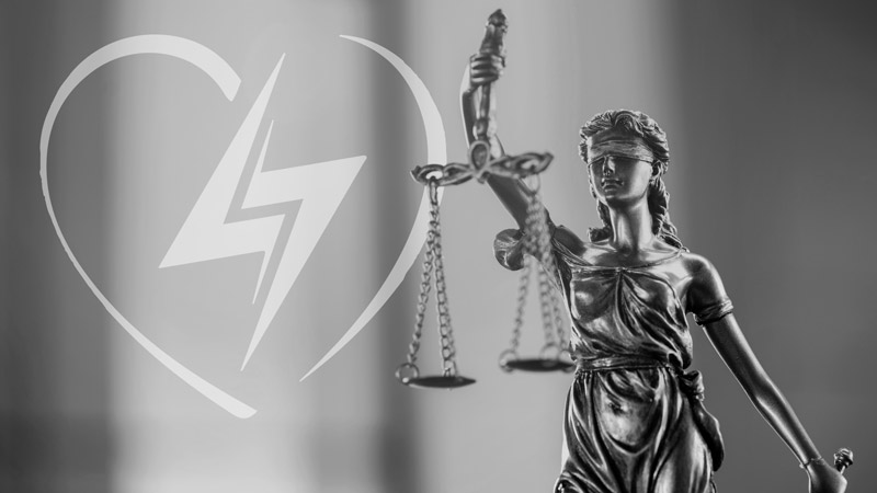 AED legislation: Lady Justice holding the scales with a heart and lightning bolt through it