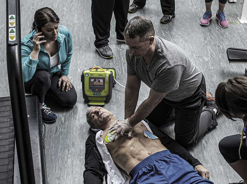 Woman calling 911 while man performs CPR on another unresponsive man while connected to a ZOLL AED 3.
